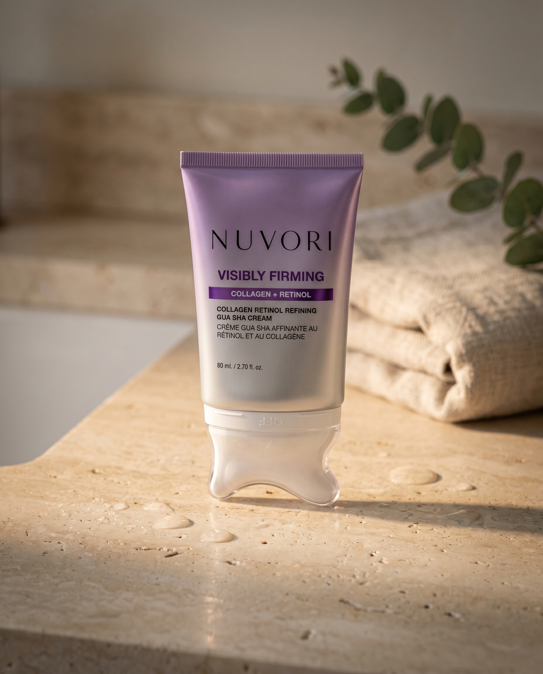 NUVORI gua sha cream on a travertine bathroom counter