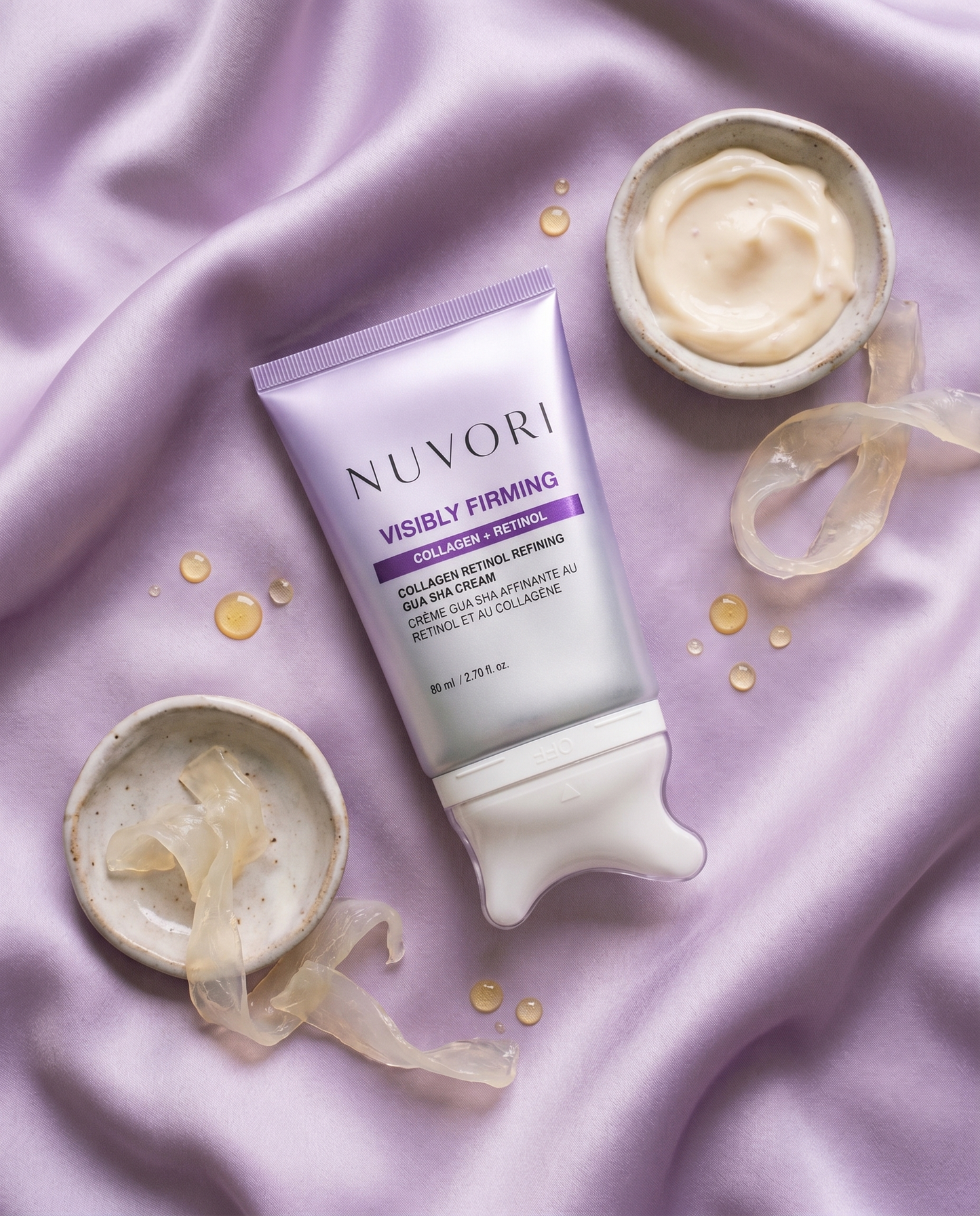 NUVORI gua sha cream flat lay with ingredient cues on lilac silk