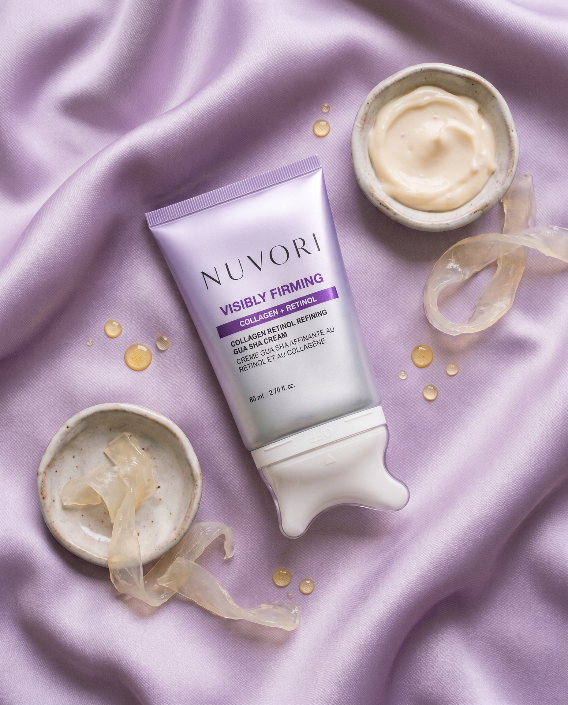 NUVORI gua sha cream flat lay with ingredient cues on lilac silk