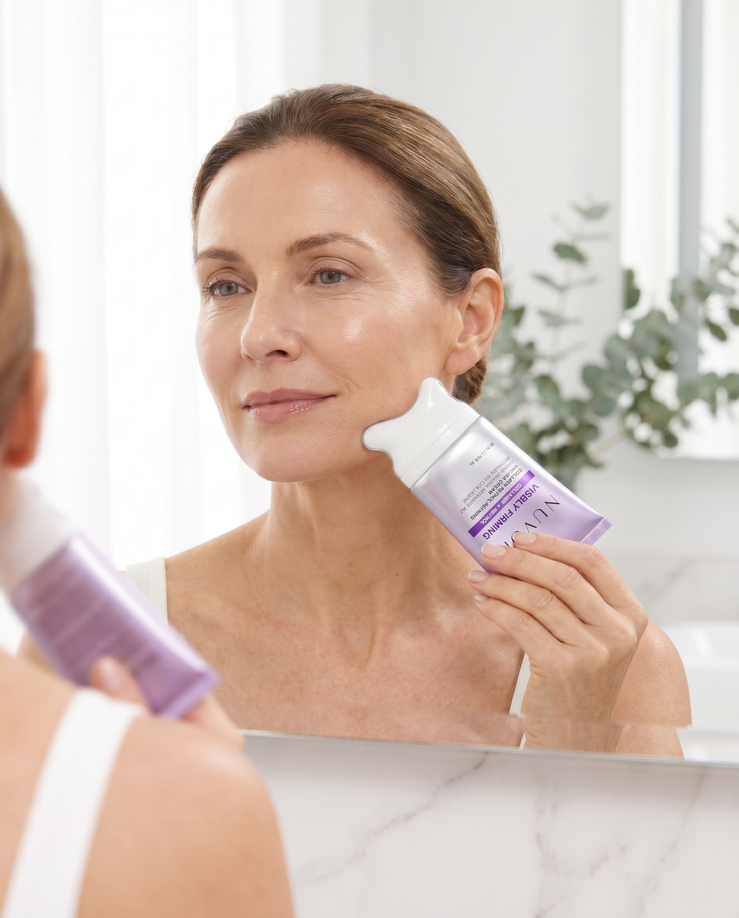 Woman gliding the NUVORI gua sha cream upward along her jawline